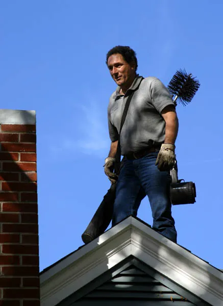 Chimney sweep standing beside a brick chimney